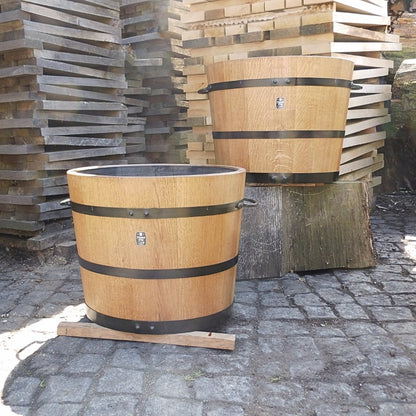 Schwarz abgebundene Eichenkübel vor gestapeltem Holz –  wenn Material und Handwerk Qualität formen